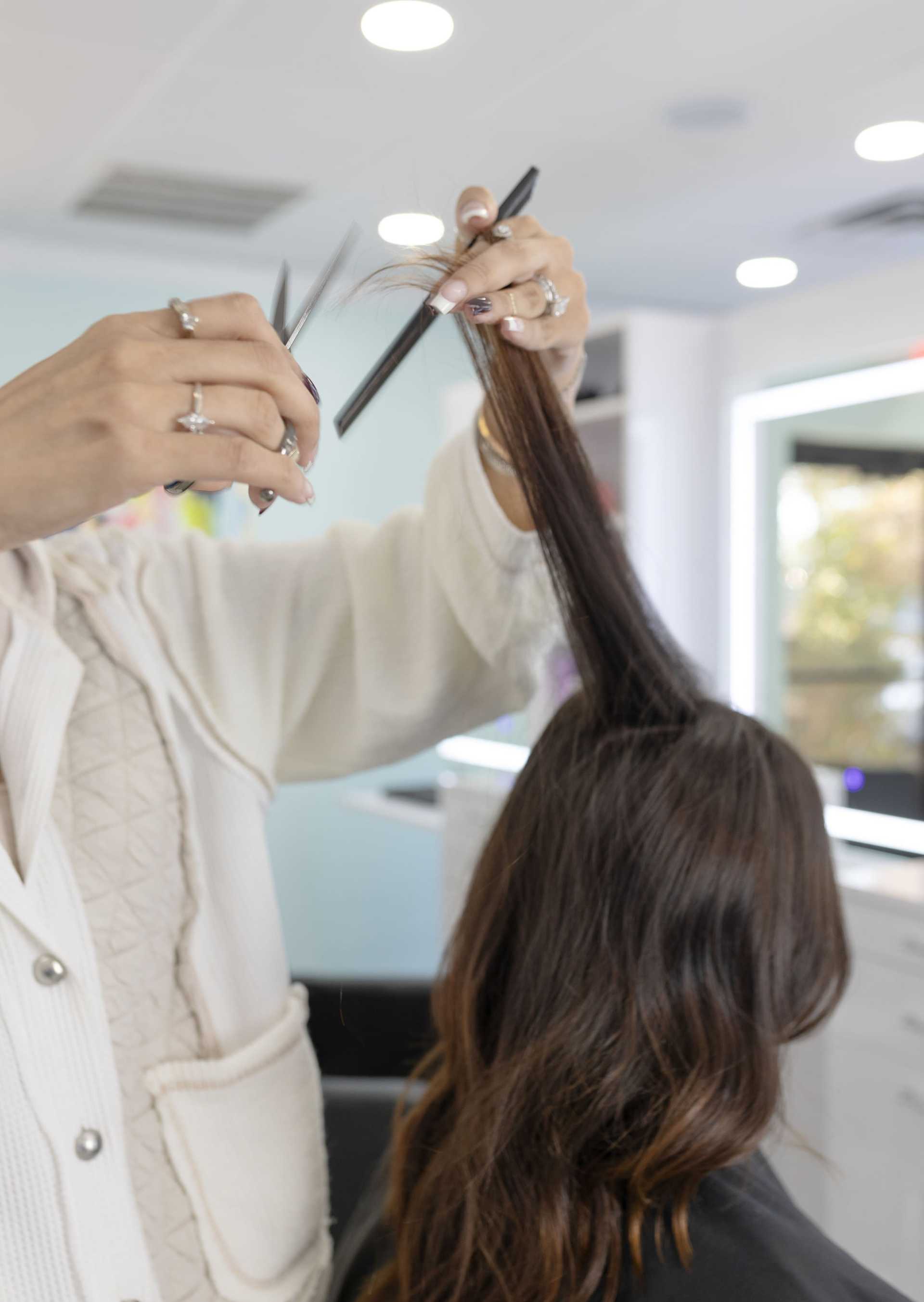 A stylist cuts a woman's hair in a salon.
